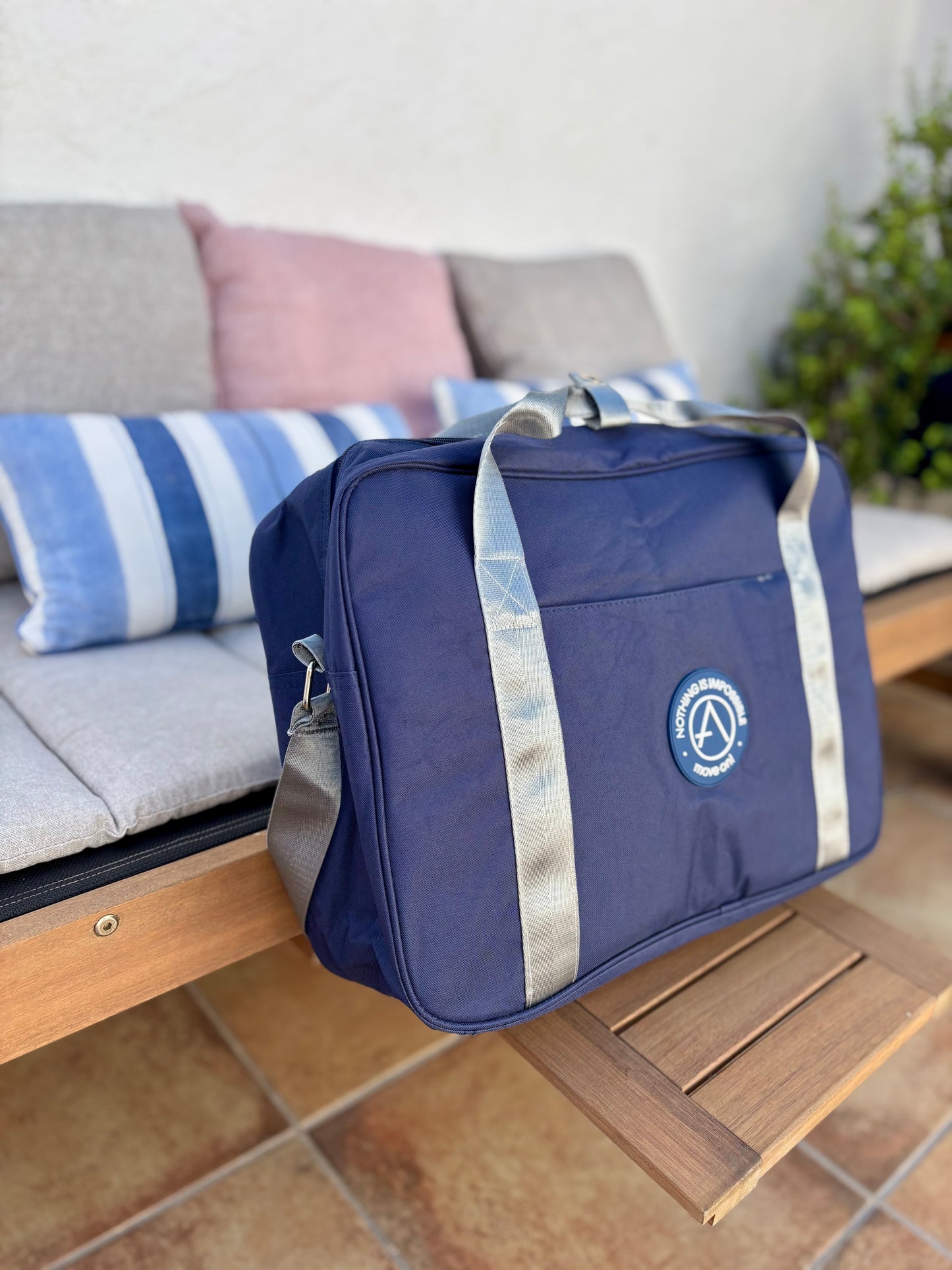 Bolsa de viaje rectangular azul marino con frase “Nothing is Impossible – Move On” y asas en gris claro