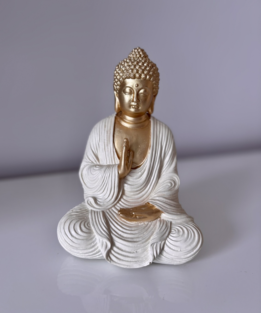Figura decorativa Buda Priya meditando en resina con acabado blanco y dorado, ideal para crear ambientes zen en salón o estantería