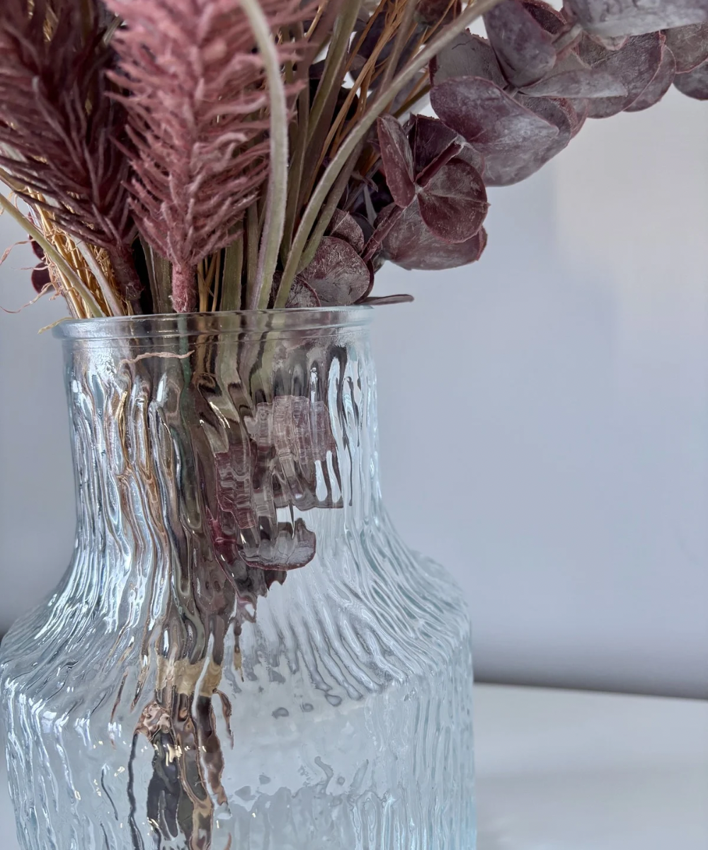 Detalle de jarrón de vidrio transparente con textura vertical y tono verdoso, diseño elegante para decoración moderna y natural