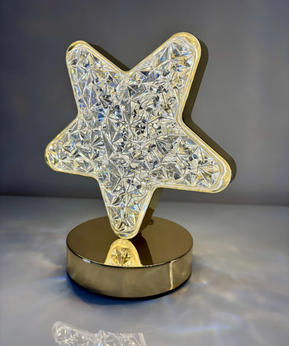 Lámpara LED estrella de acrílico tallado con base metálica dorada, ideal para iluminación ambiental elegante